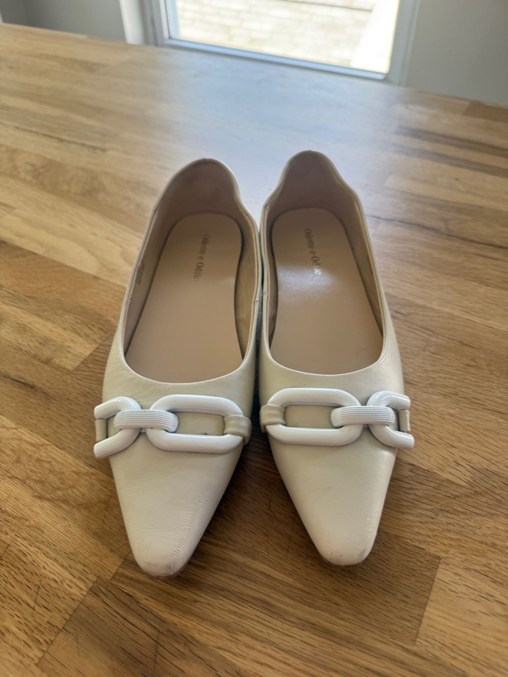Cream colored pointed toe flats with buckle detail